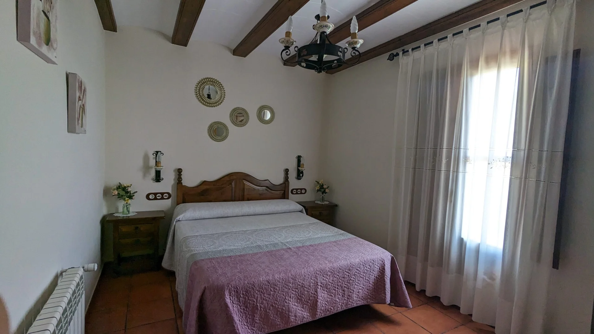 Dormitorio con cama de matrimonio, ventana y vigas de madera