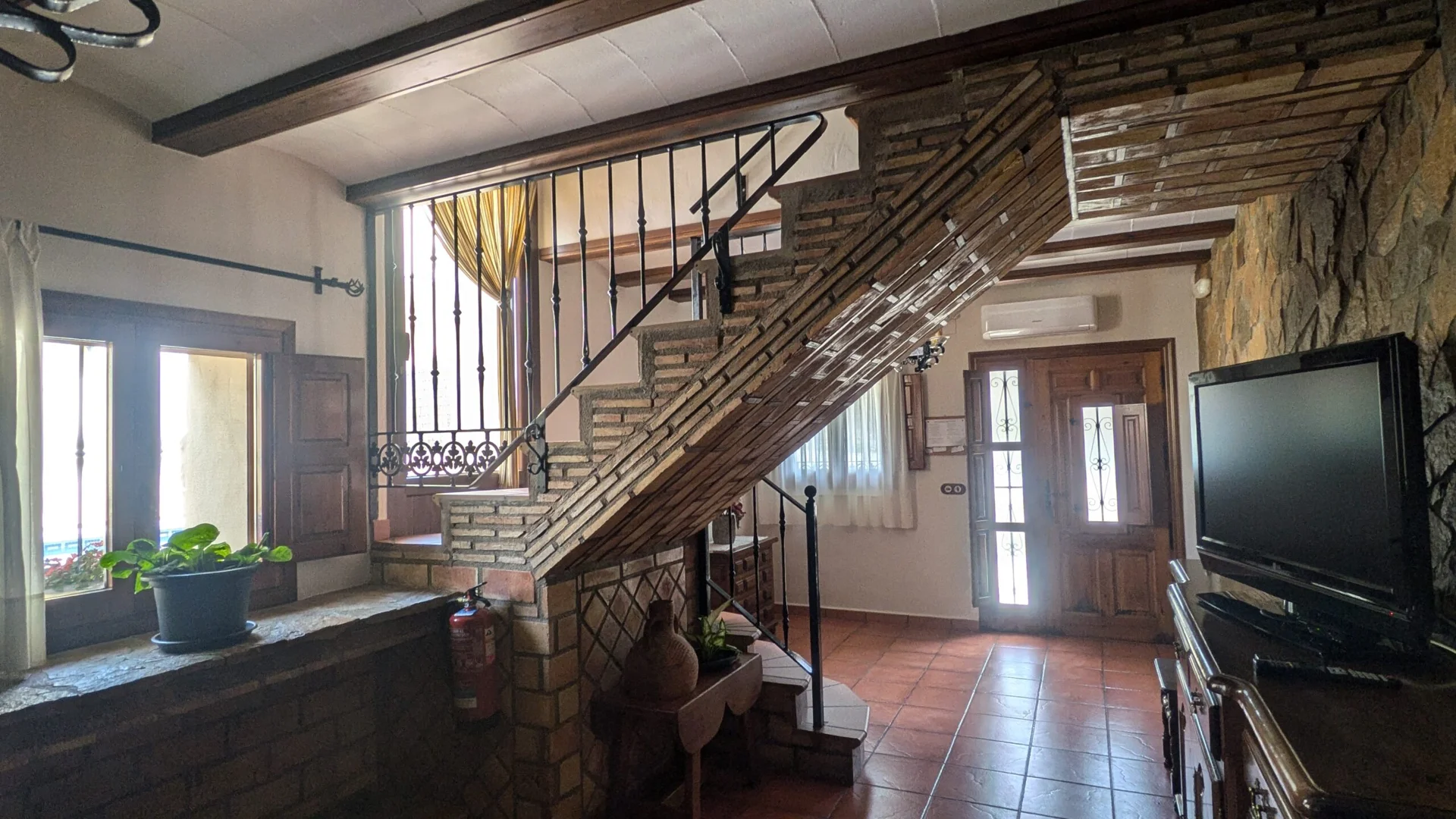 Entrada de la casa con paredes de piedra y escalera a las plantas superiores